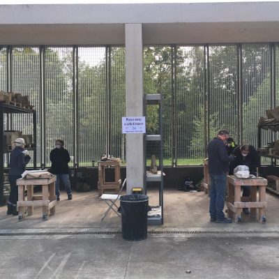 Five artists working outside with stone on bunkers, a grey concrete pillar between them