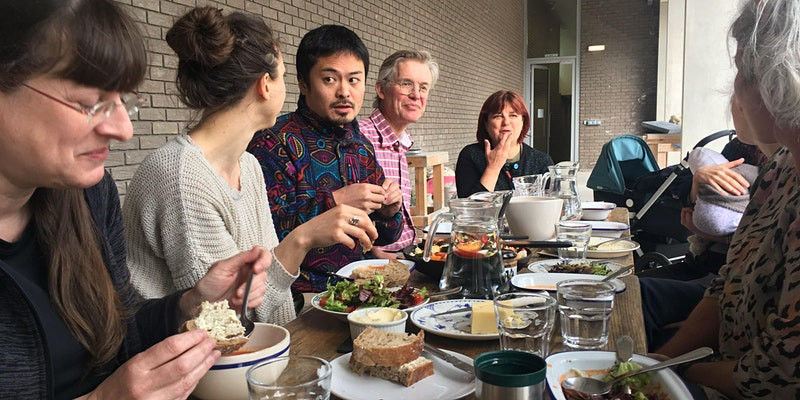 People sitting around a table outside, eating.
